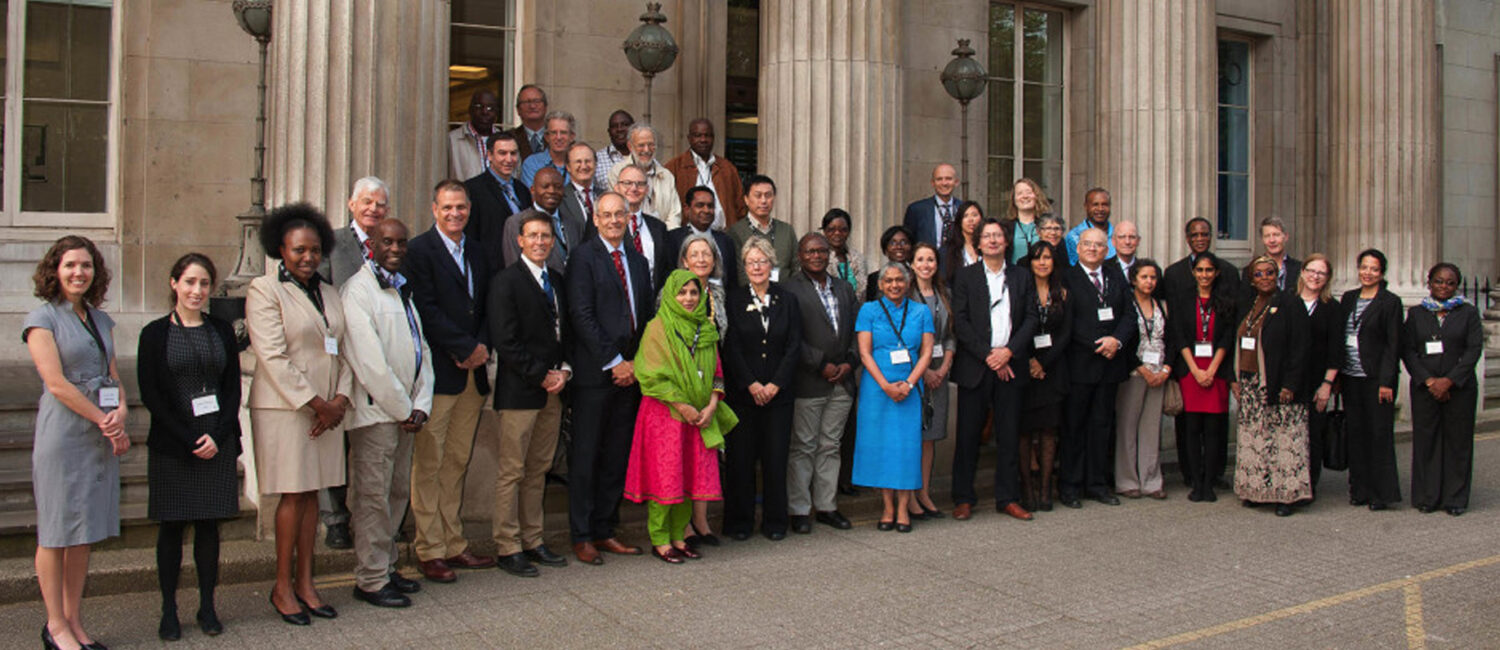 A group of people in business clothing gathered on the steps of a building with columns.