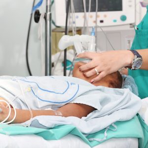 Unidentified patient receiving oxygen by a breathing mask holded by a nurse